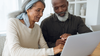 an older man and woman looking at a laptop