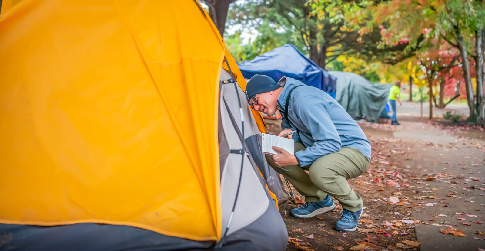 man crouched down speaking to someone in a tent