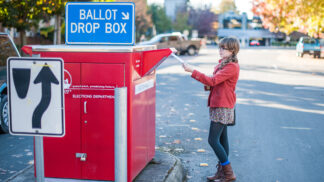 person dropping their election ballot in a drop box