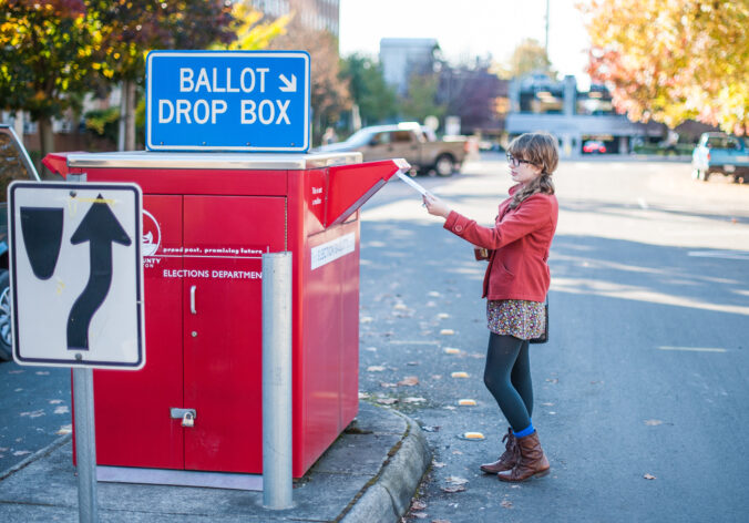 person dropping their election ballot in a drop box