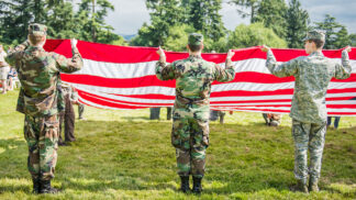 people in military uniform folding an American flag